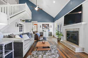 Living area featuring high vaulted ceiling, wood-type flooring, a fireplace, ceiling fan, and ornamental molding