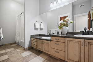Full bathroom featuring shower / bath combo with shower curtain and double vanity