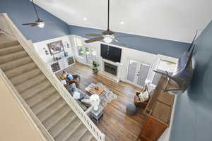 Living area featuring french doors, high vaulted ceiling, wood-type flooring, stairs, and a fireplace