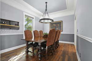 Dining room featuring crown molding, dark wood-style floors, and a chandelier