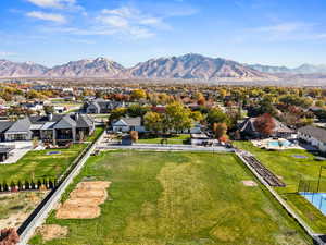 Aerial view of residential area featuring a mountainous background, horse pasture and rear view of the home
