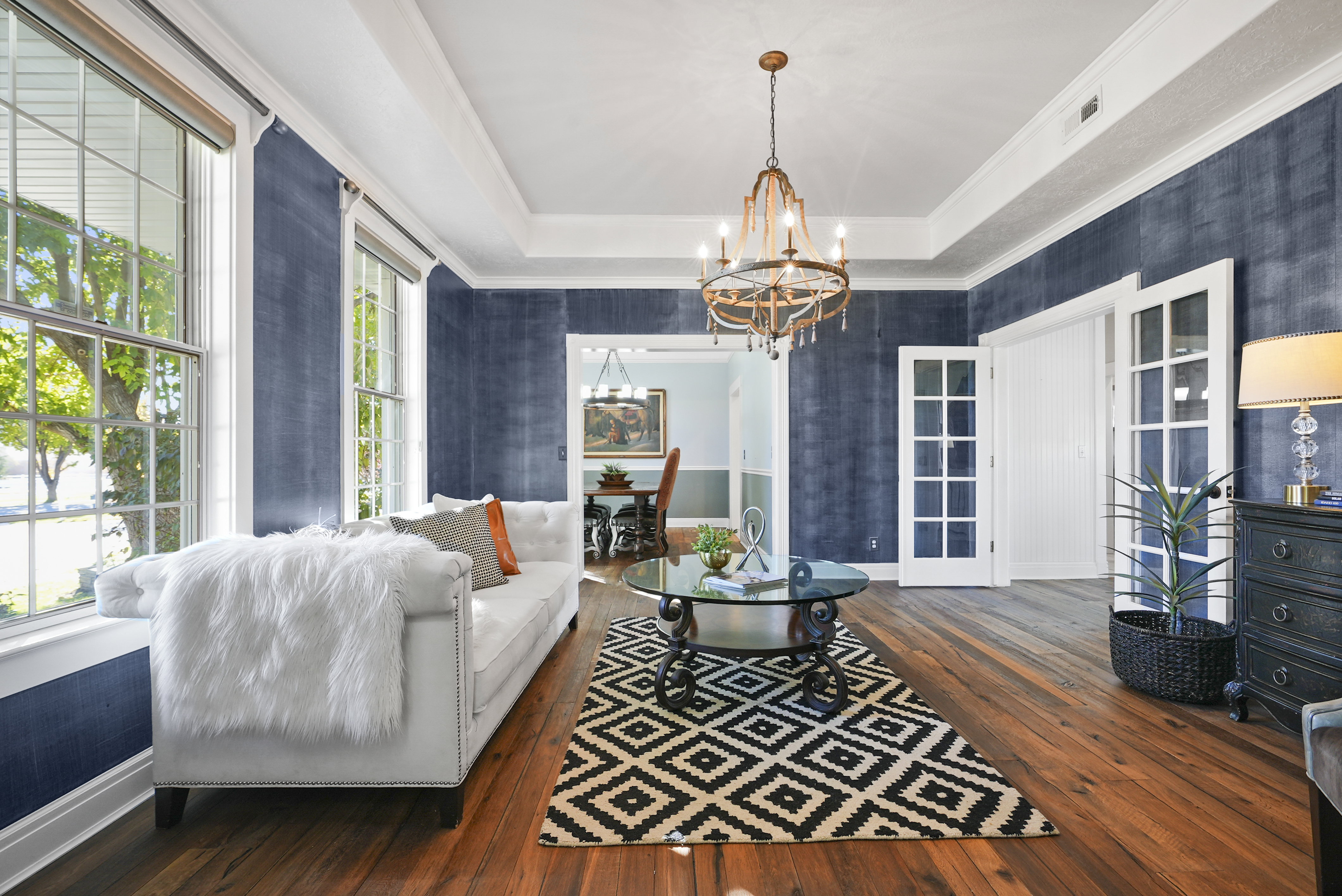 Living room featuring dark wood-type flooring, a tray ceiling, French doors, a chandelier, and crown molding
