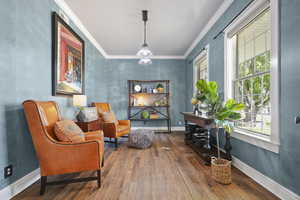 Sitting room with wood-type flooring and ornamental molding