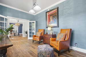 Sitting room with hardwood / wood-style flooring, ornamental molding, and a chandelier