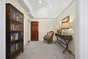 Primary Suite sitting room featuring vaulted ceiling, light carpet, and crown molding