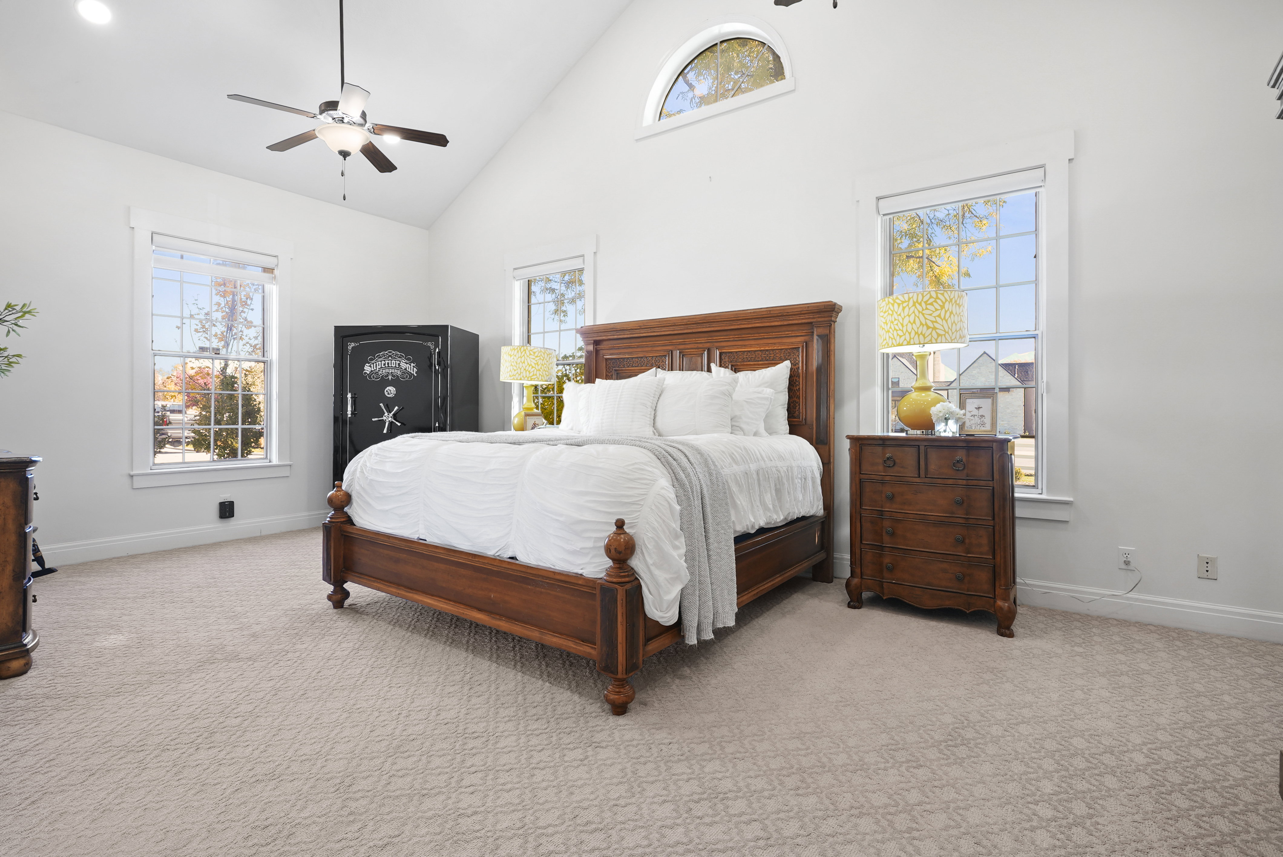 Primary Suite with high vaulted ceiling, light carpet, multiple windows, and ceiling fan