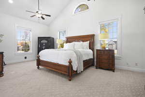 Primary Suite with high vaulted ceiling, light carpet, multiple windows, and ceiling fan