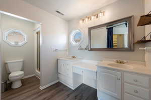 Full bathroom featuring a shower stall, dark wood-style floors, and double vanity