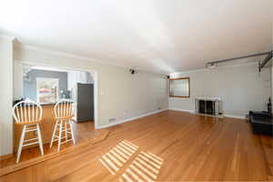 Unfurnished living room featuring crown molding, light wood-style floors, and a fireplace