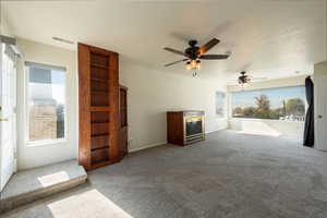 Unfurnished living room featuring carpet floors and a ceiling fan