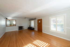 Unfurnished living room featuring ornamental molding, plenty of natural light, light wood finished floors, and a fireplace