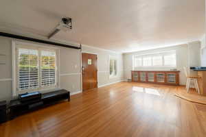 Living area with ornamental molding and light wood-style floors