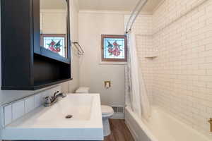 Full bath featuring shower / tub combo with curtain, dark wood-style flooring, ornamental molding, and vanity