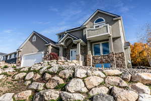 View of front of home with stone siding, stucco siding, and an attached garage