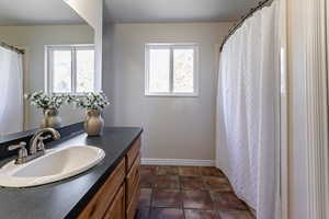 Bathroom with a shower with shower curtain, vanity, and dark tile patterned flooring