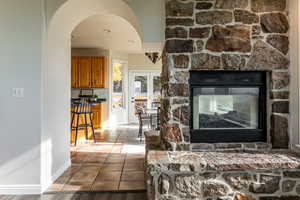 Living area featuring arched walkways, dark tile patterned floors, recessed lighting, and a stone fireplace
