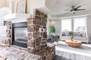 Living room with wood finished floors, a fireplace, and ceiling fan