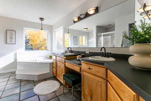 Full bath with a shower stall, double vanity, light tile patterned flooring, and a garden tub