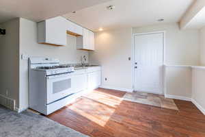 Kitchen featuring white appliances, white cabinets, wood tiled floors, and light countertops