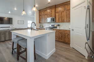Kitchen featuring brown cabinets, open floor plan, backsplash, a kitchen breakfast bar, and hanging light fixtures