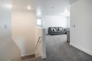 Hallway with an upstairs landing, carpet floors, and a textured ceiling