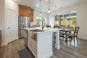 Kitchen with decorative light fixtures, an island with sink, light wood-type flooring, recessed lighting, and a kitchen bar