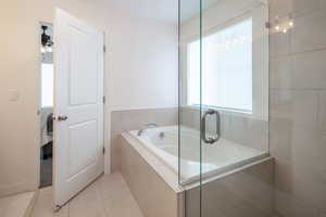Full bath with light tile patterned floors, a garden tub, and a shower stall