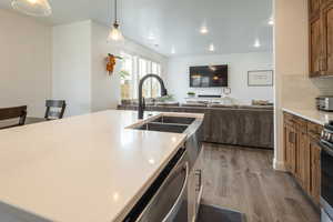 Kitchen with dark wood-style floors, open floor plan, decorative light fixtures, stainless steel appliances, and tasteful backsplash