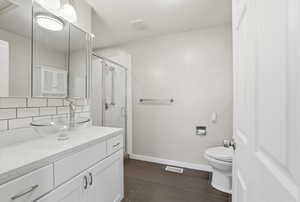 Bathroom with vanity, a shower stall, decorative backsplash, and dark tile patterned floors
