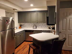 Kitchen featuring stainless steel appliances, light wood-style flooring, a peninsula, backsplash, and recessed lighting