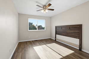 Unfurnished bedroom featuring dark wood-style flooring and a ceiling fan