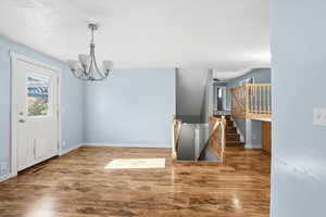 Foyer entrance featuring wood finished floors, a chandelier, and a textured ceiling