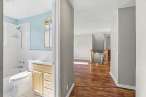 Bathroom featuring vanity, bathtub / shower combination, light wood-type flooring, and a wainscoted wall