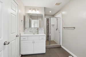 Bathroom with vanity, a shower stall, and decorative backsplash