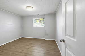 Unfurnished room with wood finished floors and ornamental molding