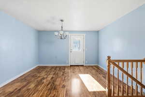 Foyer with wood finished floors and a chandelier