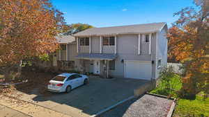 Traditional-style home with driveway, roof with shingles, and an attached garage
