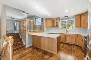 Kitchen with dark wood finished floors, light countertops, glass insert cabinets, appliances with stainless steel finishes, and recessed lighting