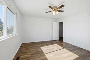 Unfurnished room with dark wood-type flooring and ceiling fan
