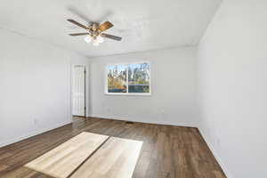 Spare room featuring dark wood-type flooring, a ceiling fan, and a textured ceiling