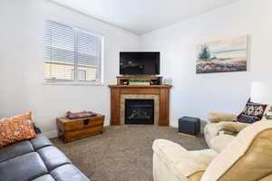 Carpeted living room featuring a tile fireplace and baseboards