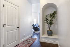 Hallway with dark wood-type flooring and baseboards