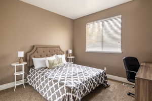 Carpeted bedroom featuring baseboards and an office area