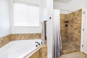 Full bath with a bath, a shower stall, and plenty of natural light