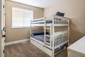 Bedroom featuring dark colored carpet and baseboards