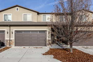 Traditional-style home featuring stucco siding, concrete driveway, an attached garage, and stone siding