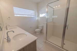 Bathroom with light tile patterned floors, double vanity, and a stall shower