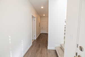 Corridor featuring dark wood-style flooring, recessed lighting, and stairway