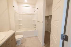 Full bath featuring vanity, light tile patterned flooring, a walk in closet, and bathing tub / shower combination