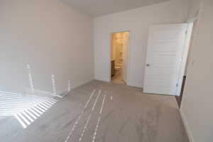 Unfurnished bedroom with carpet flooring and ensuite bath